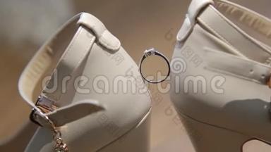 女白鞋上的结婚戒指。 新娘白鞋上漂亮的结婚戒指。 白色婚礼订婚